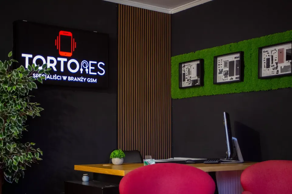 Wnętrze salonu Tortores w Rzeszowie: podświetlone logo, zielona ściana z mchu i stanowisko obsługi