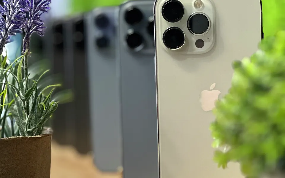 Srebrny iPhone Pro z bliska, w tle kolejne iPhone’y i lawenda na półce w salonie Tortores