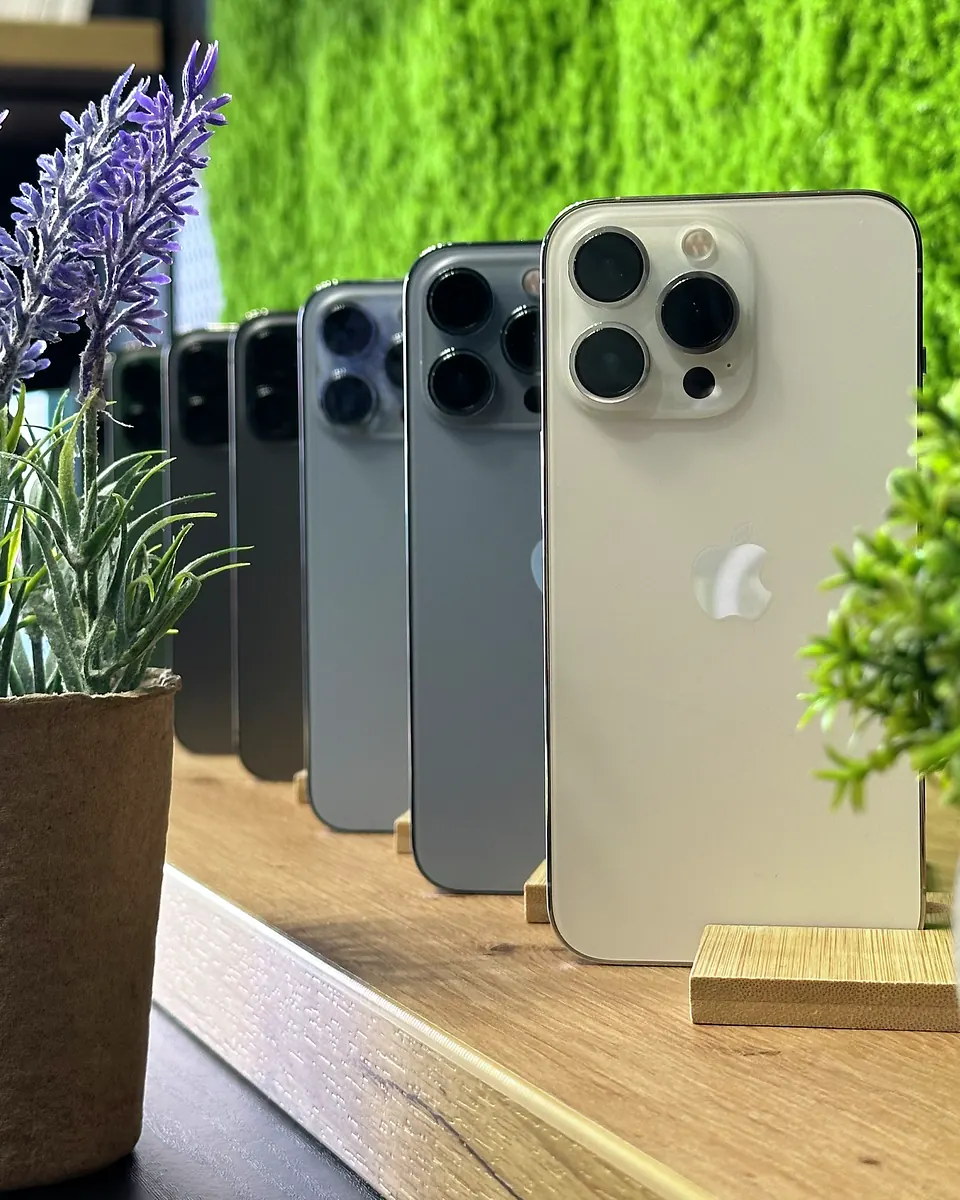 iPhone’y Pro w rzędzie na półce w salonie Tortores, ujęcie pionowe