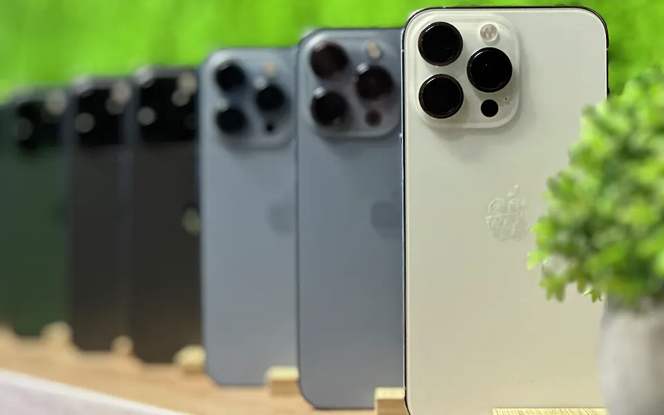 iPhone’y ustawione w rzędzie na drewnianej półce przy zielonej ścianie w salonie Tortores w Rzeszowie